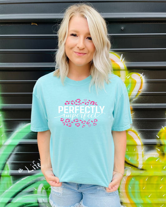 This Perfectly Imperfect Graphic Tee is crafted using Comfort Colors brand, offering all-day comfort and a vintage look. The Chalky Mint color is complemented by the vibrant pink design, while the oversized fit creates a stylish, relaxed silhouette.