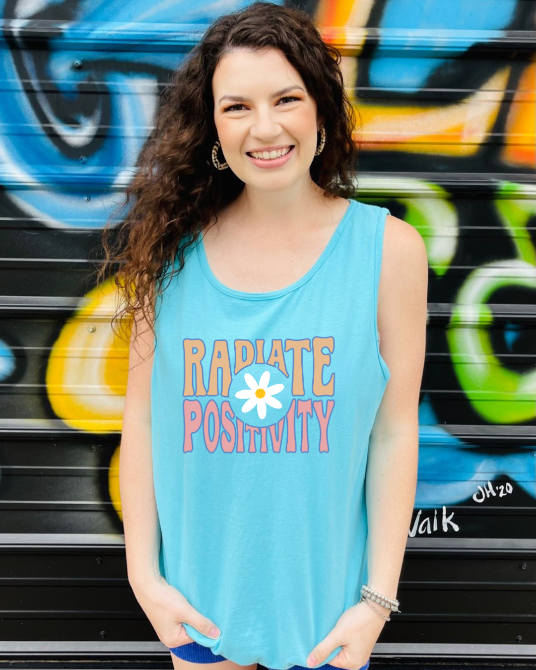 This Radiate Positivity Graphic Tank from Comfort Colors is the perfect addition to your wardrobe. With its bright blue hue and vibrant daisy design, it'll let you show off your cheerful personality. Put it on and spread those good vibes!